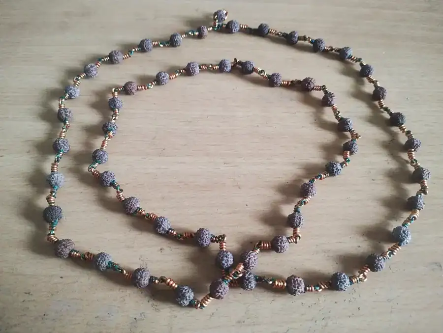 A knotted Rudraksha necklace laid out on a pale surface