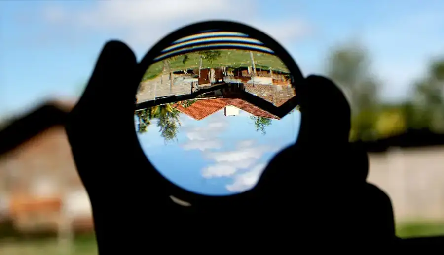 A hand-held magnifying lens showing an inverted outdoor view