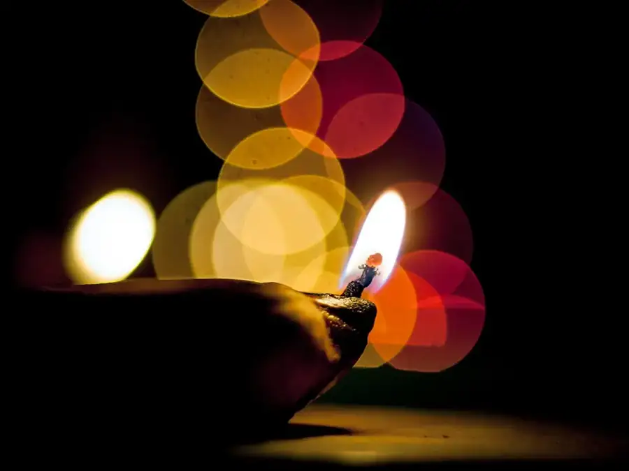 An oil lamp glowing beside warm out-of-focus festival lights