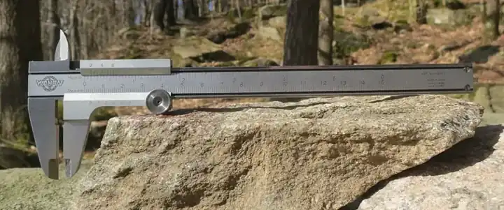 A metal vernier caliper photographed on a textured surface